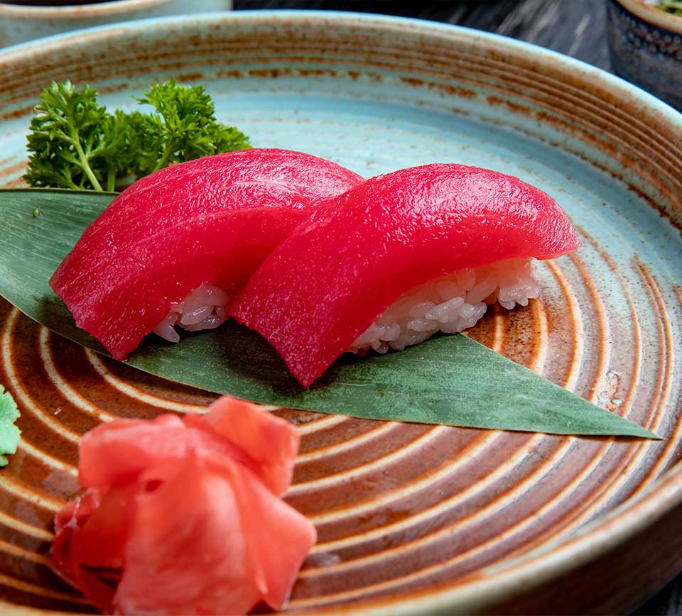 side-view-nigiri-sushi-with-tuna-bamboo-leaf-served-with-pickled-ginger-slices-wasabi-plate